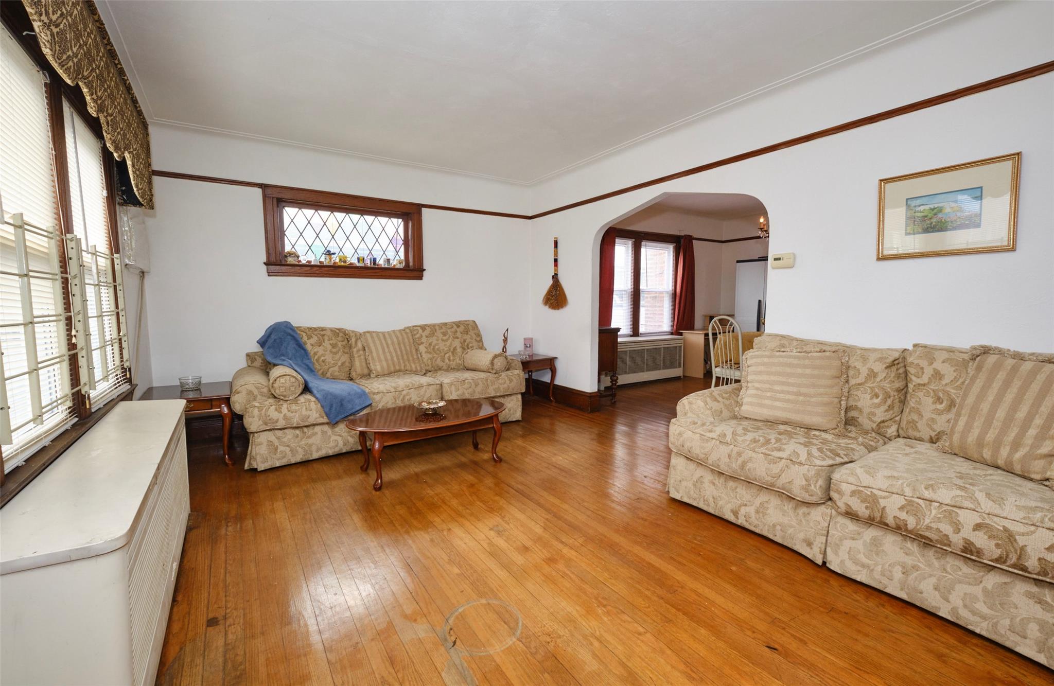135-47 229th Street Queens, NY 11413 - Photo 4 of 36 Living area with a healthy amount of sunlight, radiator, hardwood / wood-style flooring, and arched walkways