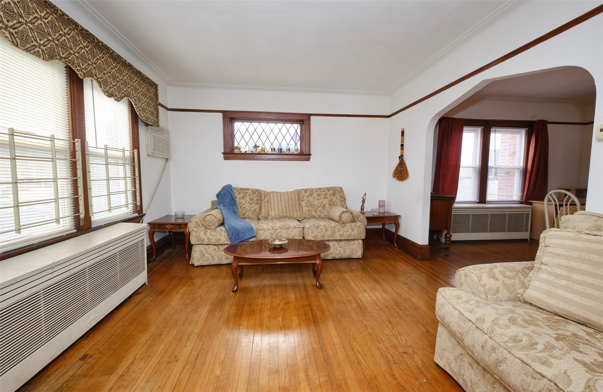 135-47 229th Street Queens, NY 11413 - Photo 5 of 36 Living area with radiator heating unit, arched walkways, hardwood / wood-style floors, and ornamental molding