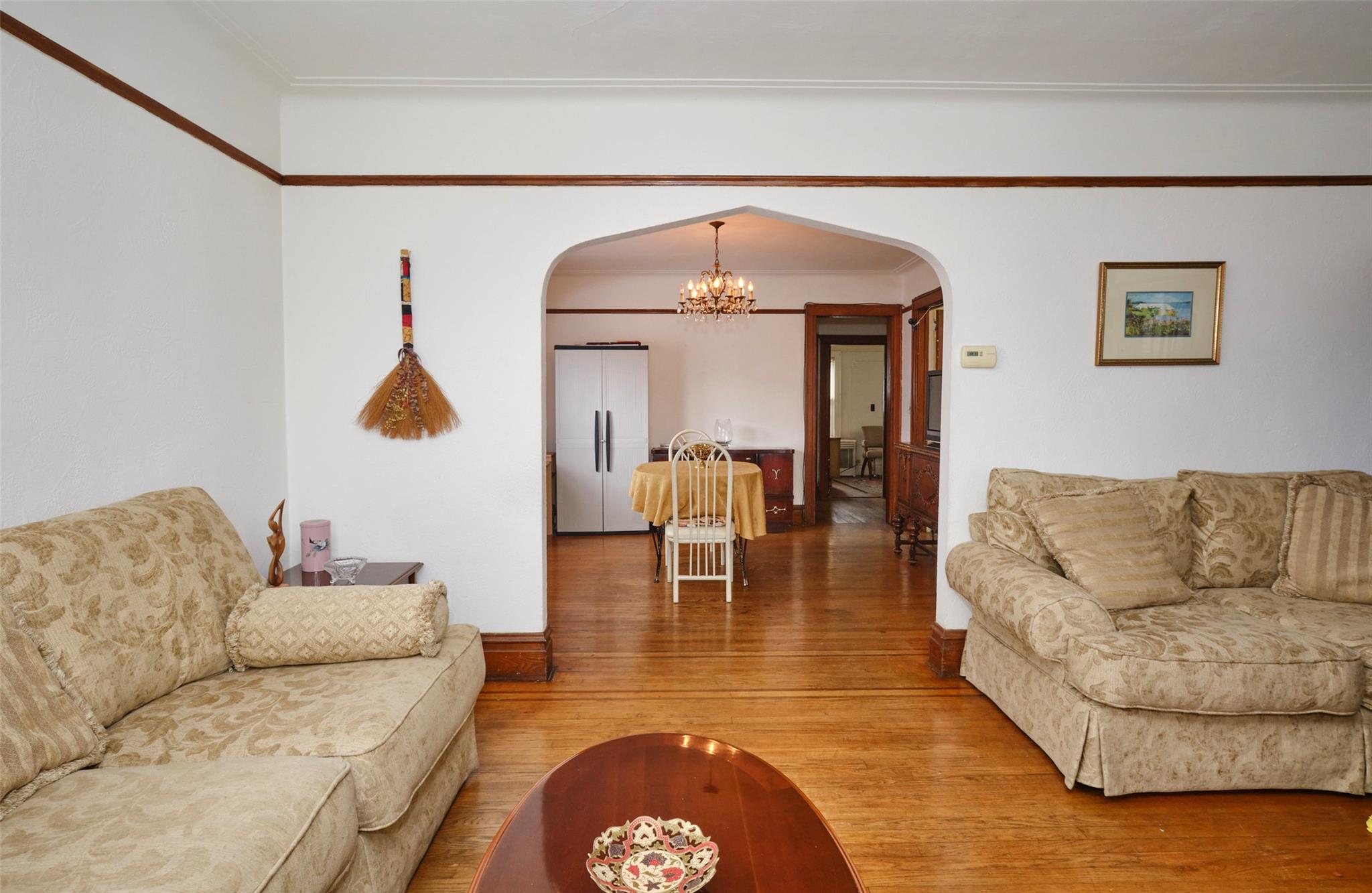 135-47 229th Street Queens, NY 11413 - Photo 6 of 36 Living room featuring ornamental molding, arched walkways, a notable chandelier, and wood finished floors