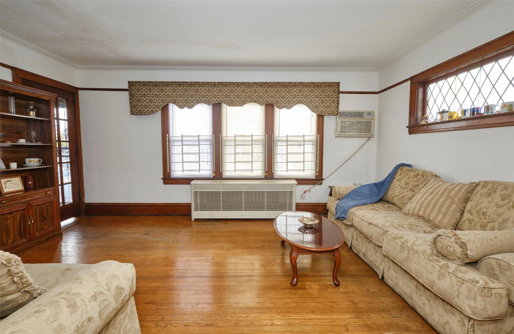 135-47 229th Street Queens, NY 11413 - Photo 8 of 36 Living room featuring ornamental molding, baseboards, radiator heating unit, and wood finished floors
