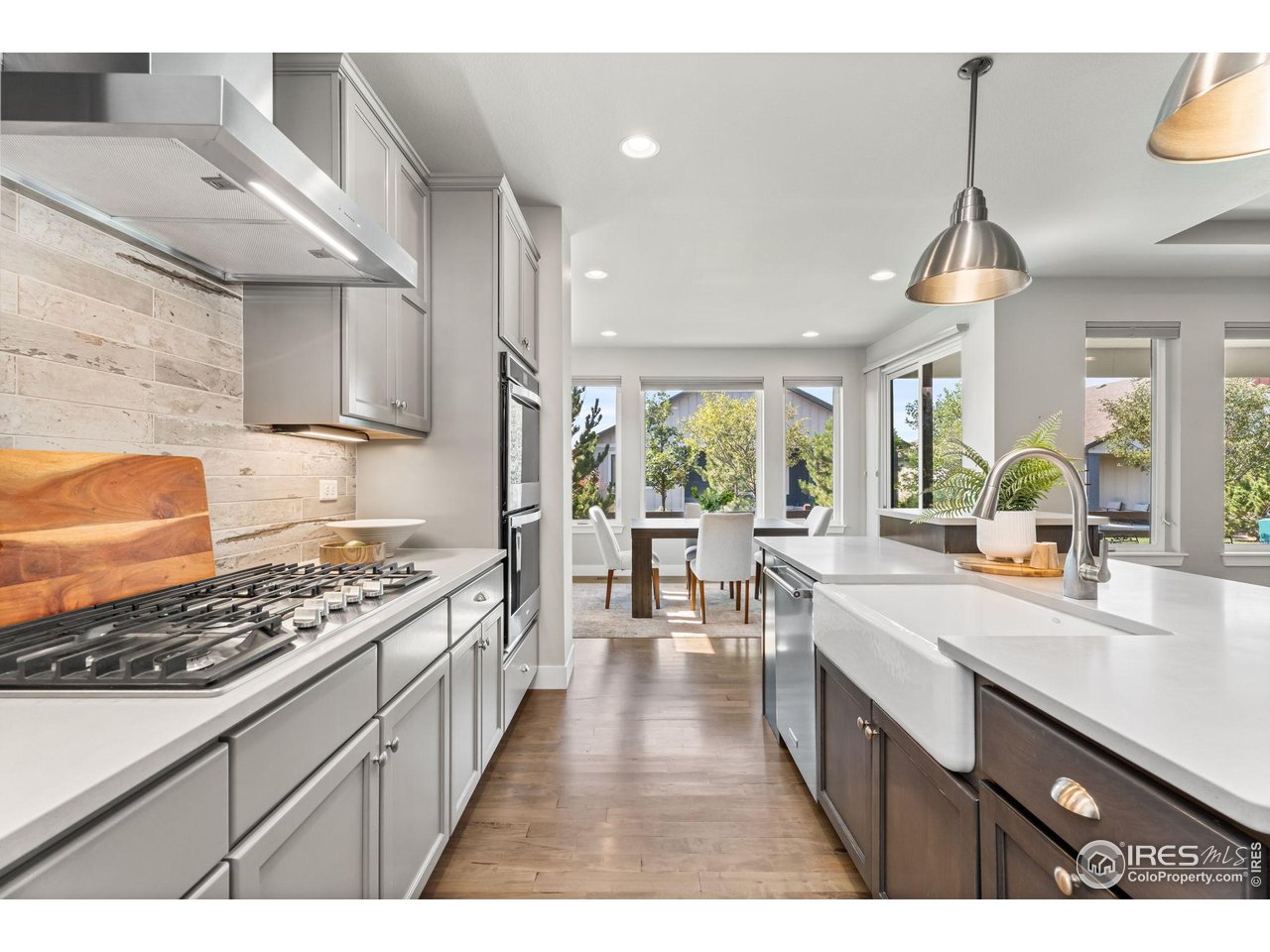 6977 Foxton Court Timnath, CO 80547 - Photo 14 of 32 a kitchen with kitchen island granite countertop lots of counter top space a sink a window and stainless steel appliances