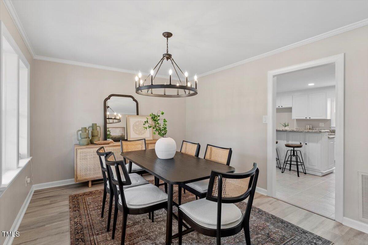 7300 Grist Mill Road Raleigh, NC 27615 - Photo 6 of 41 a view of a dining room with furniture a chandelier and wooden floor