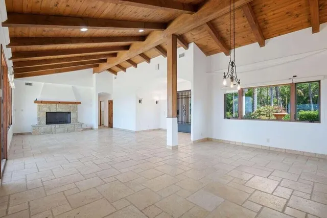 a view of an empty room with a fireplace and window