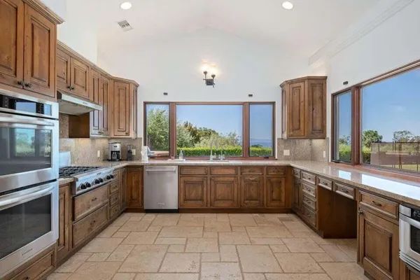 a large kitchen with stainless steel appliances granite countertop a stove sink and cabinets