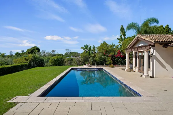 a view of swimming pool with seating area and trees in the background