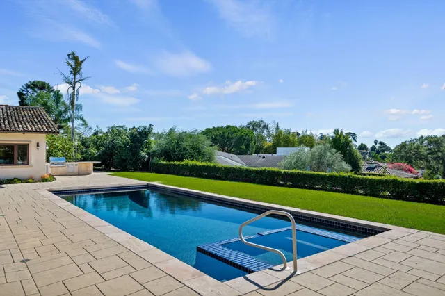 a view of swimming pool that has lawn chairs with plants
