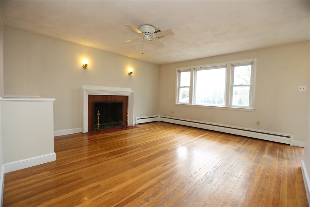 12 Lasell Street Boston, MA 02132 - Photo 3 of 22 an empty room with wooden floor and a fireplace