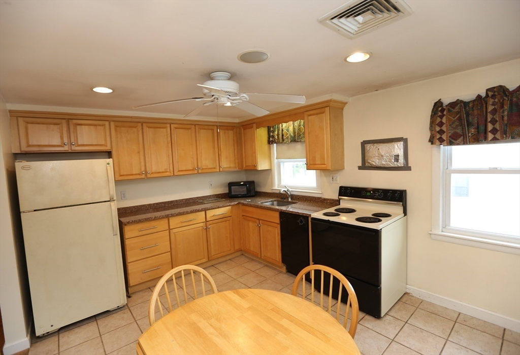 12 Lasell Street Boston, MA 02132 - Photo 5 of 22 a kitchen with stainless steel appliances granite countertop a stove a refrigerator a sink a refrigerator white cabinets and wooden floor