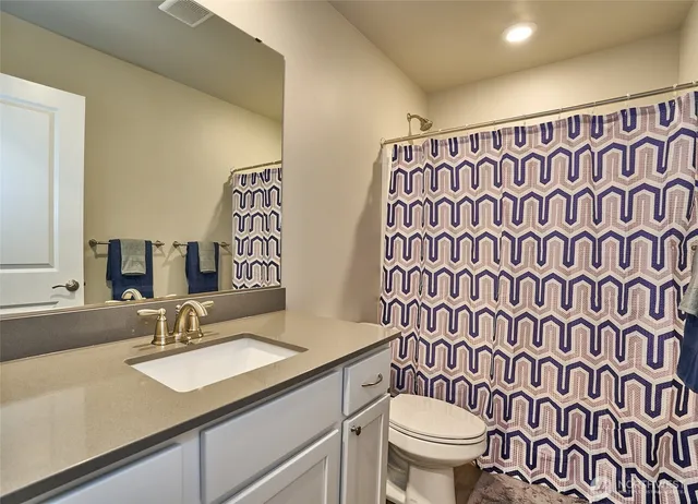 a bathroom with a granite countertop sink a toilet and a mirror