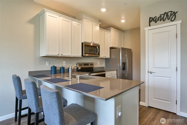 a kitchen with kitchen island granite countertop a table chairs microwave and refrigerator