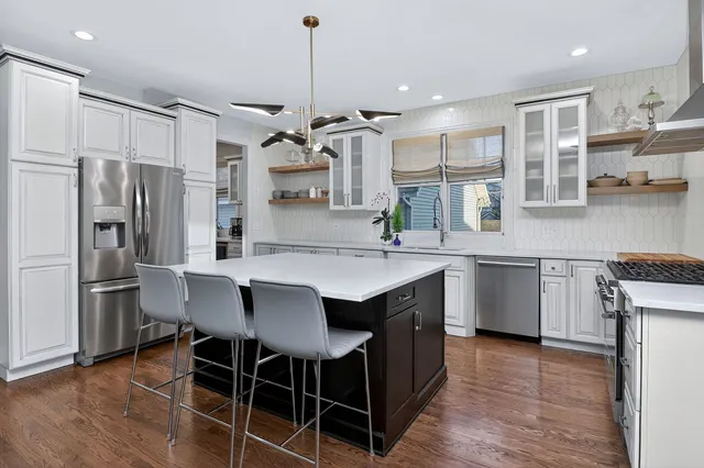 a kitchen with kitchen island granite countertop a sink a counter space stainless steel appliances and cabinets