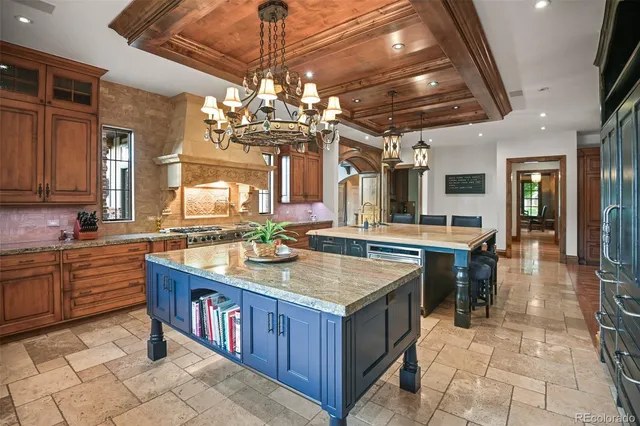 a large kitchen with kitchen island a sink a stove and a chandelier