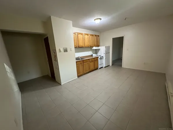 a view of a kitchen with refrigerator and white cabinets