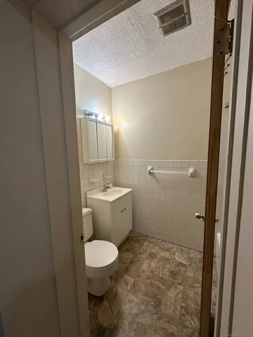 a bathroom with a granite countertop toilet a sink and a mirror