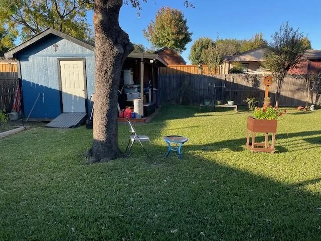 a view of a backyard with table and chairs potted plants and large tree