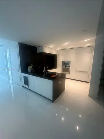 a large white kitchen with a sink and stainless steel appliances