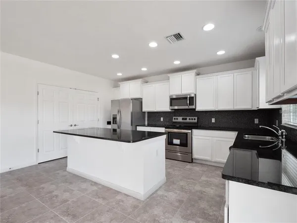 a kitchen with granite countertop a sink and white cabinets