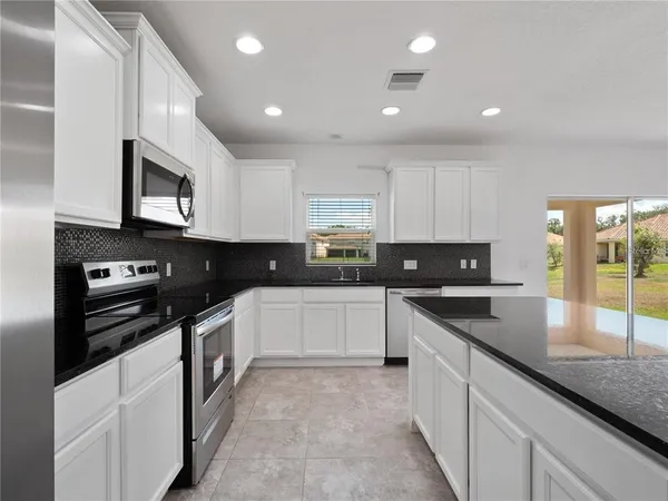 a kitchen with stainless steel appliances granite countertop a stove a sink and a microwave
