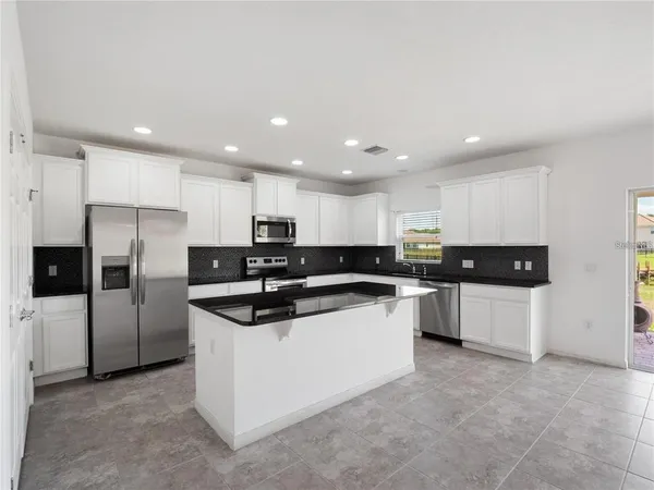 a kitchen with stainless steel appliances granite countertop a sink and white cabinets