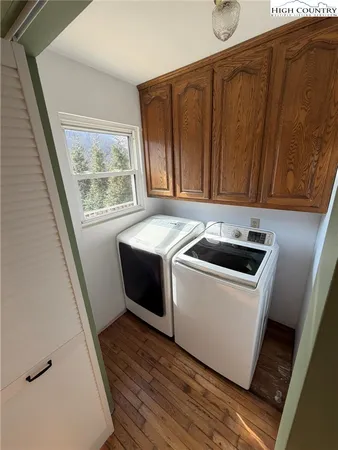 a utility room with wooden floor washer and dryer