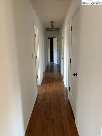 a view of a hallway with wooden floor and a bathroom