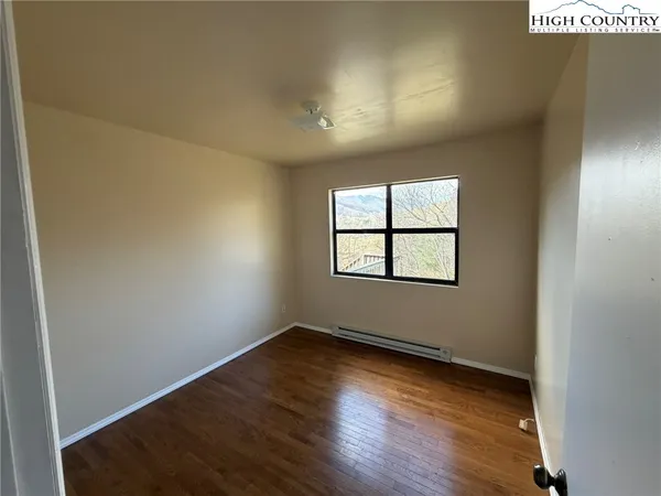 an empty room with wooden floor and windows