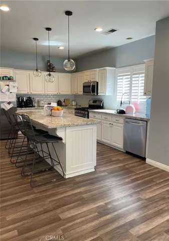 a kitchen with stainless steel appliances kitchen island granite countertop a sink a stove and a wooden floors