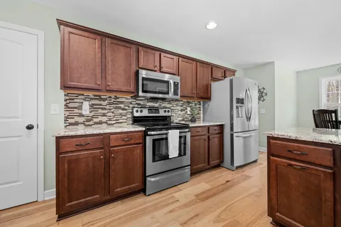 a view of a house with a yard and a large tree