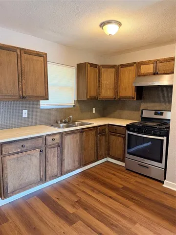 a kitchen with granite countertop a stove cabinets and wooden floor