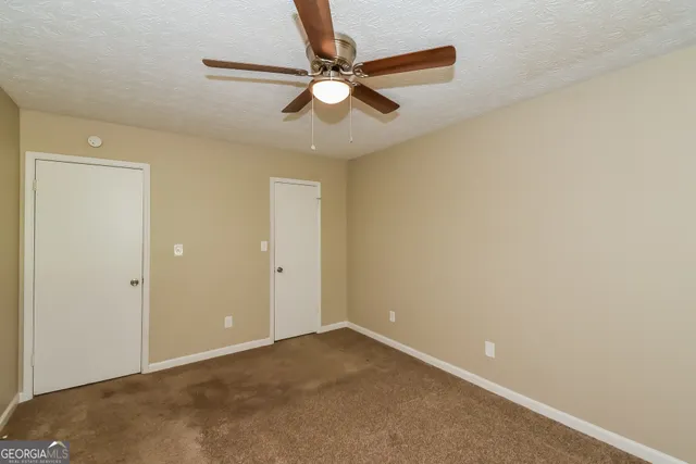 an empty room with closet and ceiling fan
