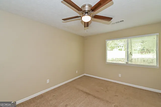 an empty room with a window and a fan
