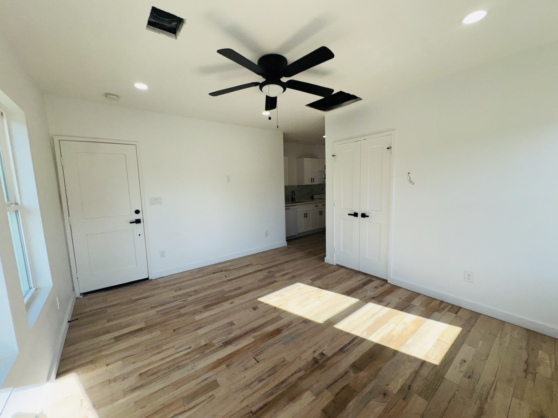 an empty room with wooden floor and ceiling fan