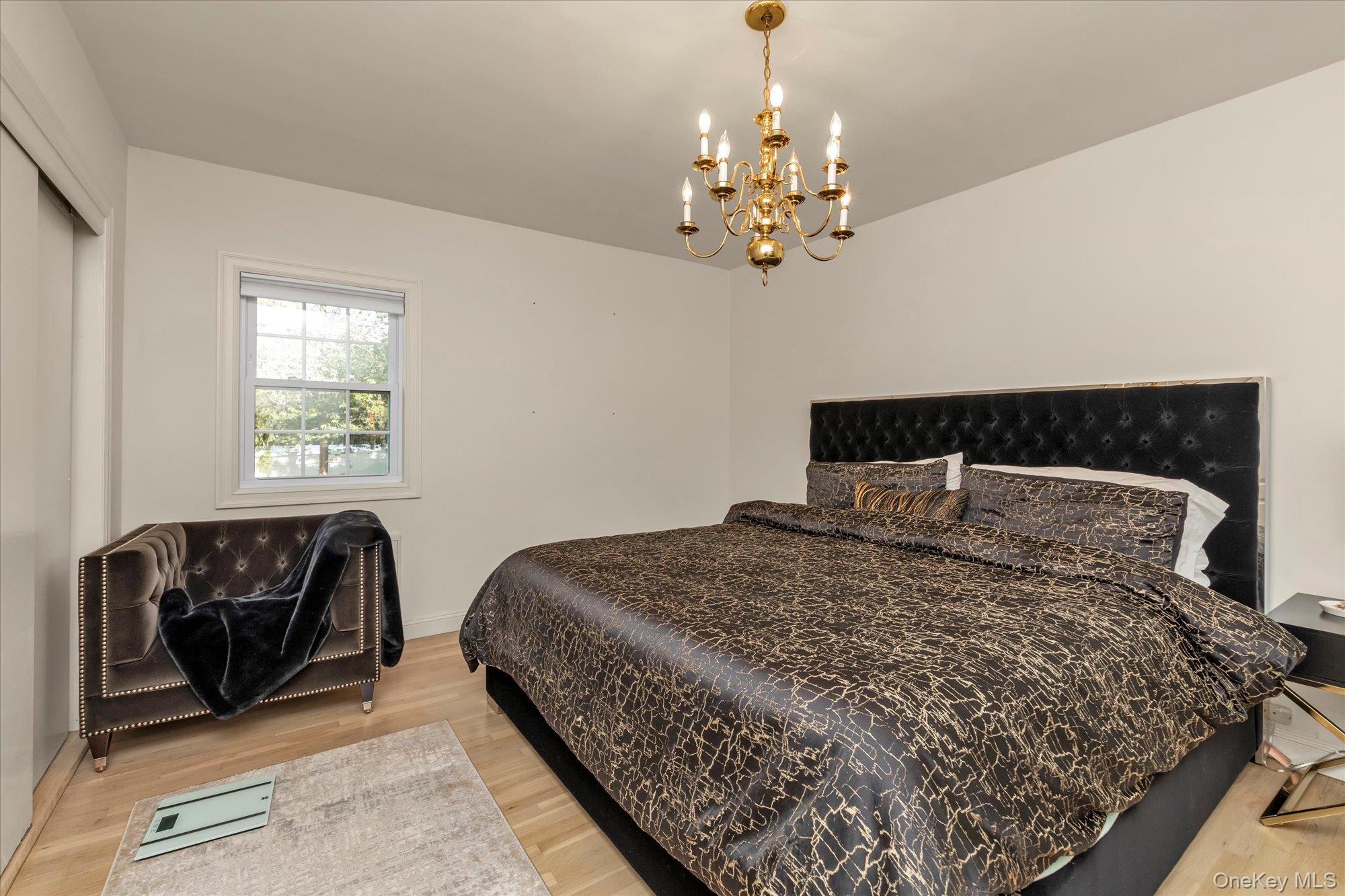 47 Pinewood Road Roslyn, NY 11576 - Photo 15 of 22 a bed sitting in a bedroom next to a window and a chandelier