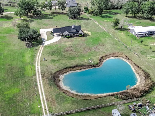 an aerial view of a house with outdoor space and trees all around