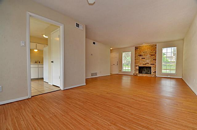 an empty room with wooden floor and a fireplace