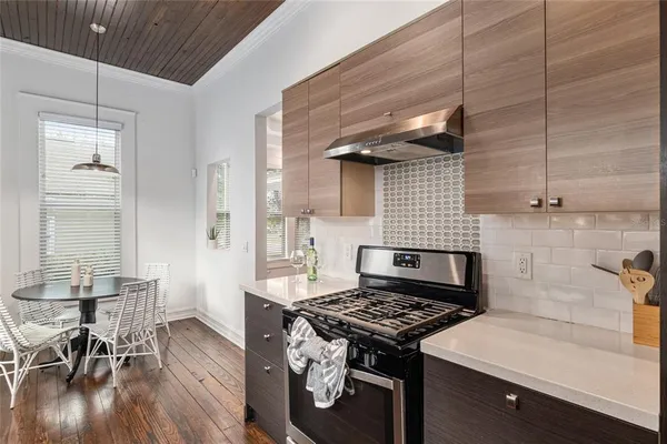 a kitchen with granite countertop a refrigerator a sink dishwasher a stove and white countertops with wooden floor