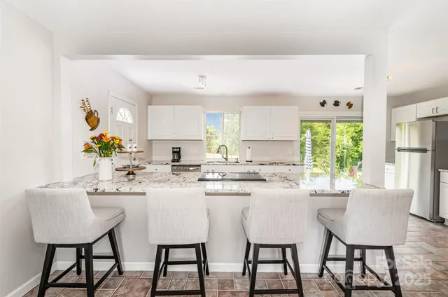 a kitchen with stainless steel appliances granite countertop a table and chairs in it