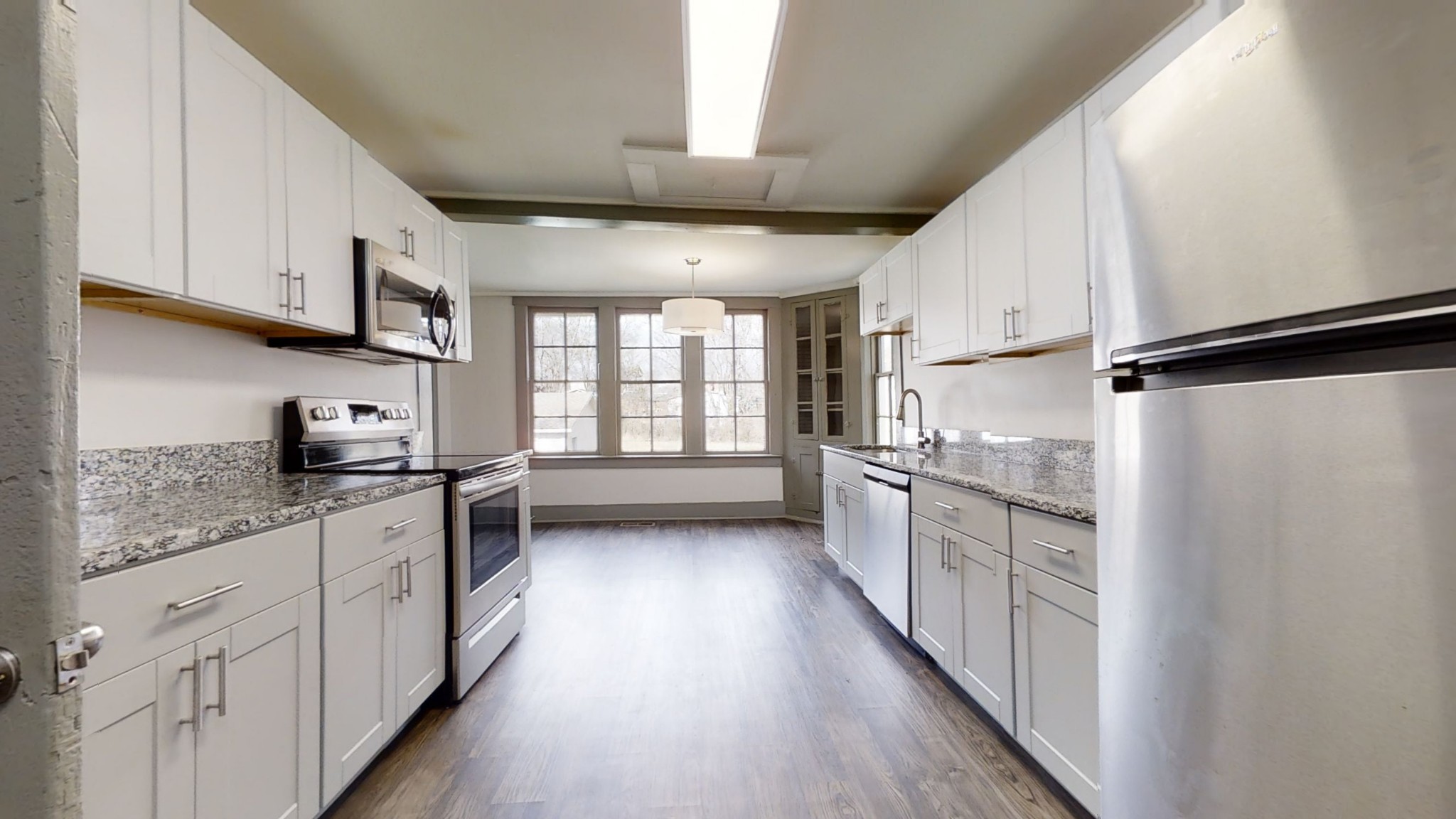 a kitchen with stainless steel appliances white cabinets and wooden floors