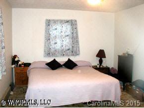 22 Tyler Street Clyde, NC 28721 - Photo 4 of 9 a bedroom with a bed and a lamp on dresser