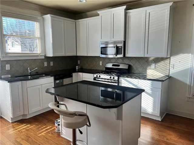 a kitchen with kitchen island granite countertop a sink a stove and cabinets