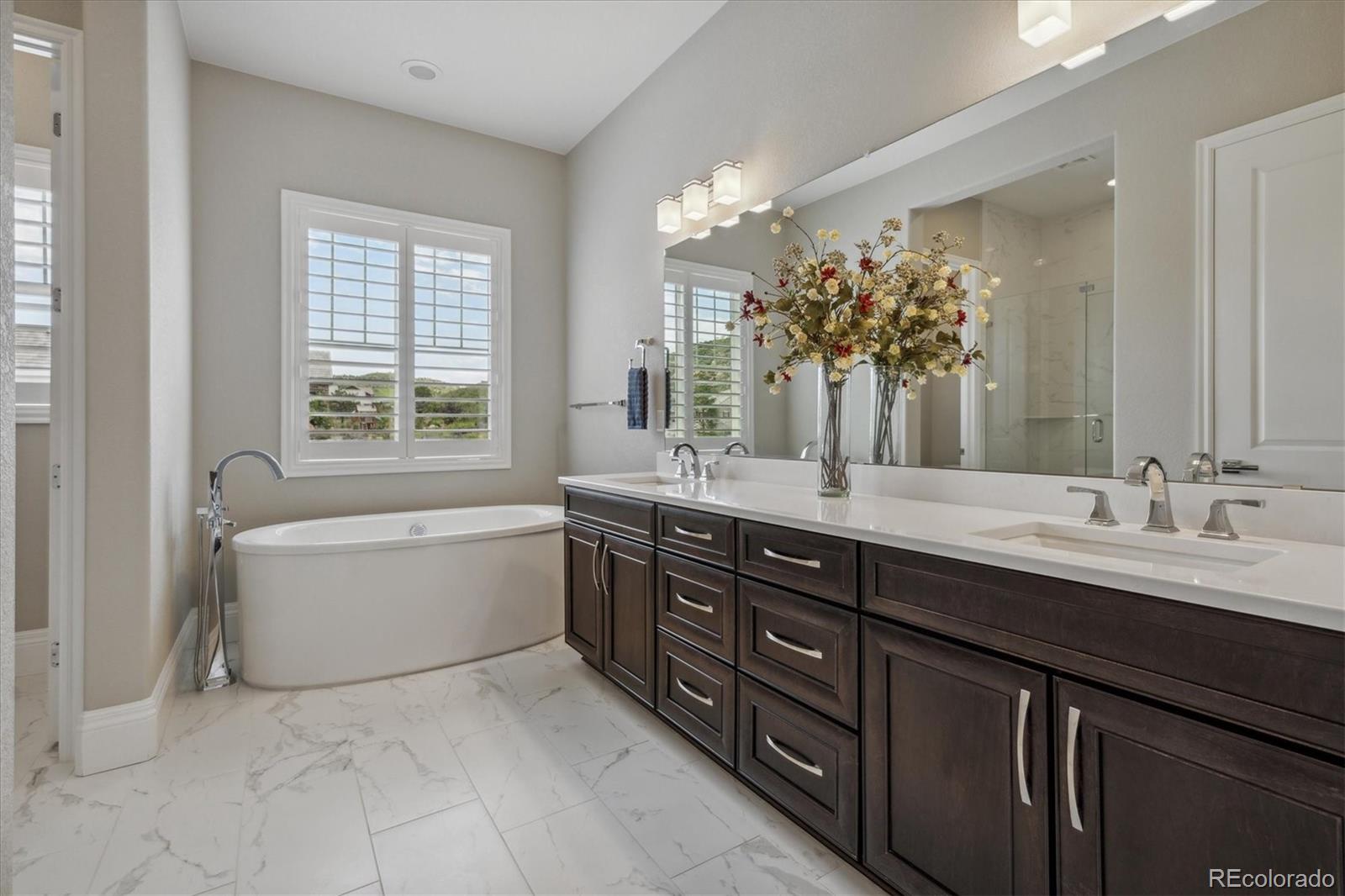 4837 Hogback Ridge Road Morrison, CO 80465 - Photo 22 of 40 a spacious bathroom with a granite countertop double vanity sink a bathtub and window