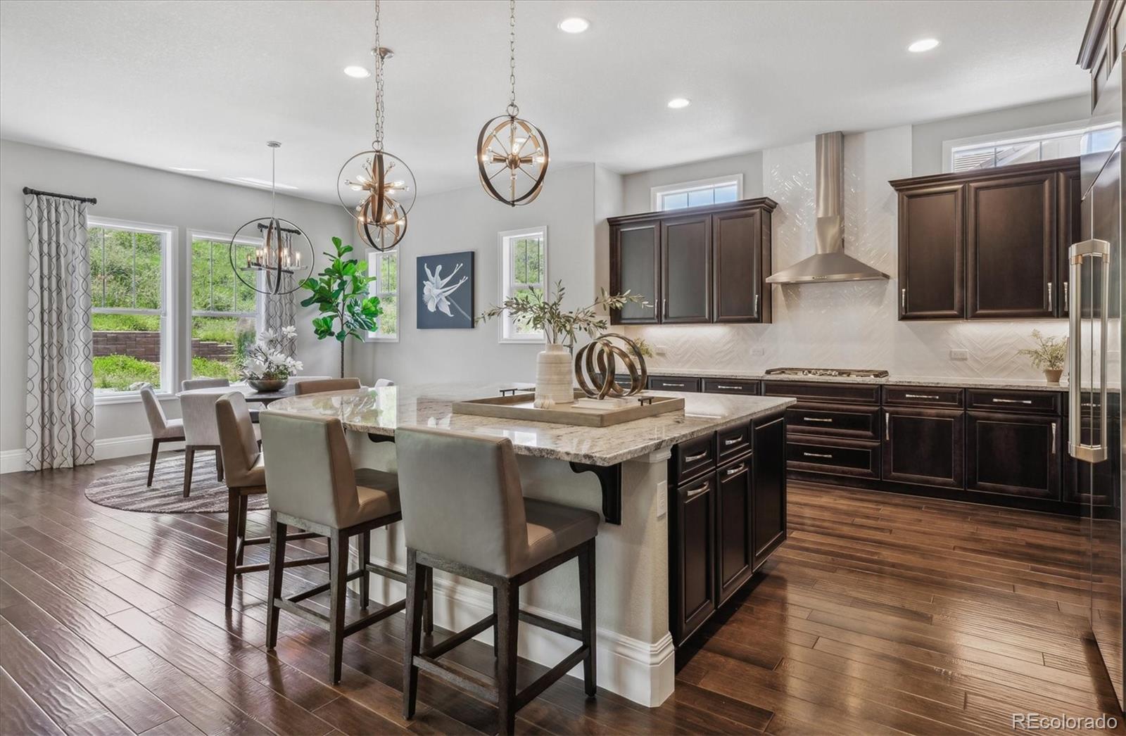 4837 Hogback Ridge Road Morrison, CO 80465 - Photo 10 of 40 a kitchen with stainless steel appliances granite countertop wooden floors a stove a sink and a refrigerator
