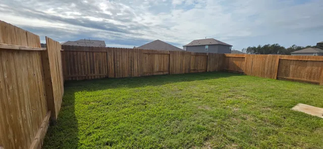 a view of a backyard with wooden fence