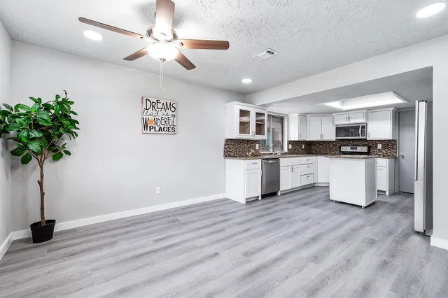 a kitchen with granite countertop a refrigerator oven a sink and wooden floor