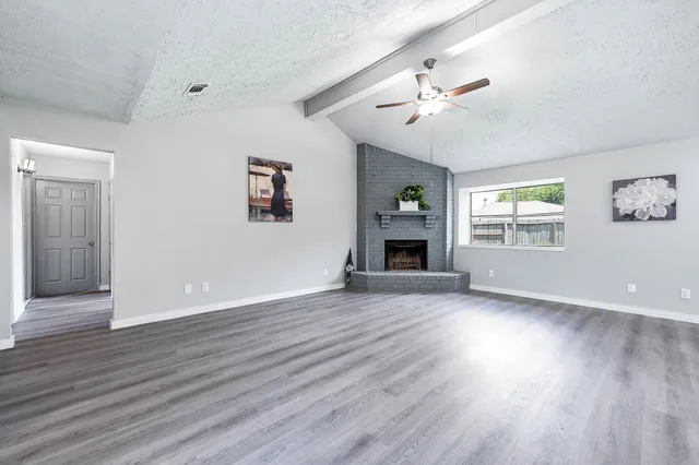 an empty room with wooden floor chandelier and windows