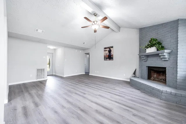 an empty room with wooden floor a fireplace and windows