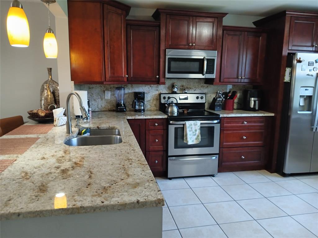 55 Southeast 14th Street, Unit 1120 Boca Raton, FL 33432 - Photo 6 of 24 a kitchen with stainless steel appliances granite countertop wooden cabinets a stove top oven a sink and dishwasher