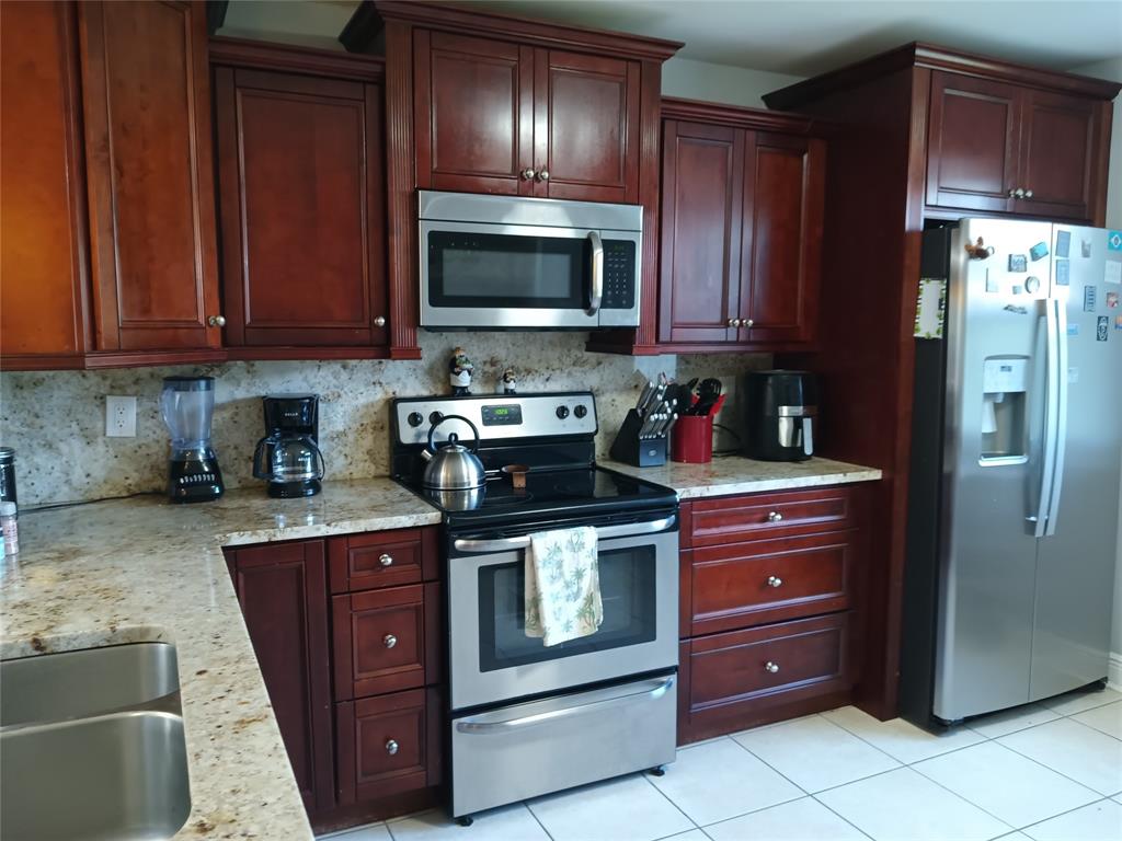 55 Southeast 14th Street, Unit 1120 Boca Raton, FL 33432 - Photo 7 of 24 a kitchen with stainless steel appliances granite countertop wooden cabinets and a stove top oven