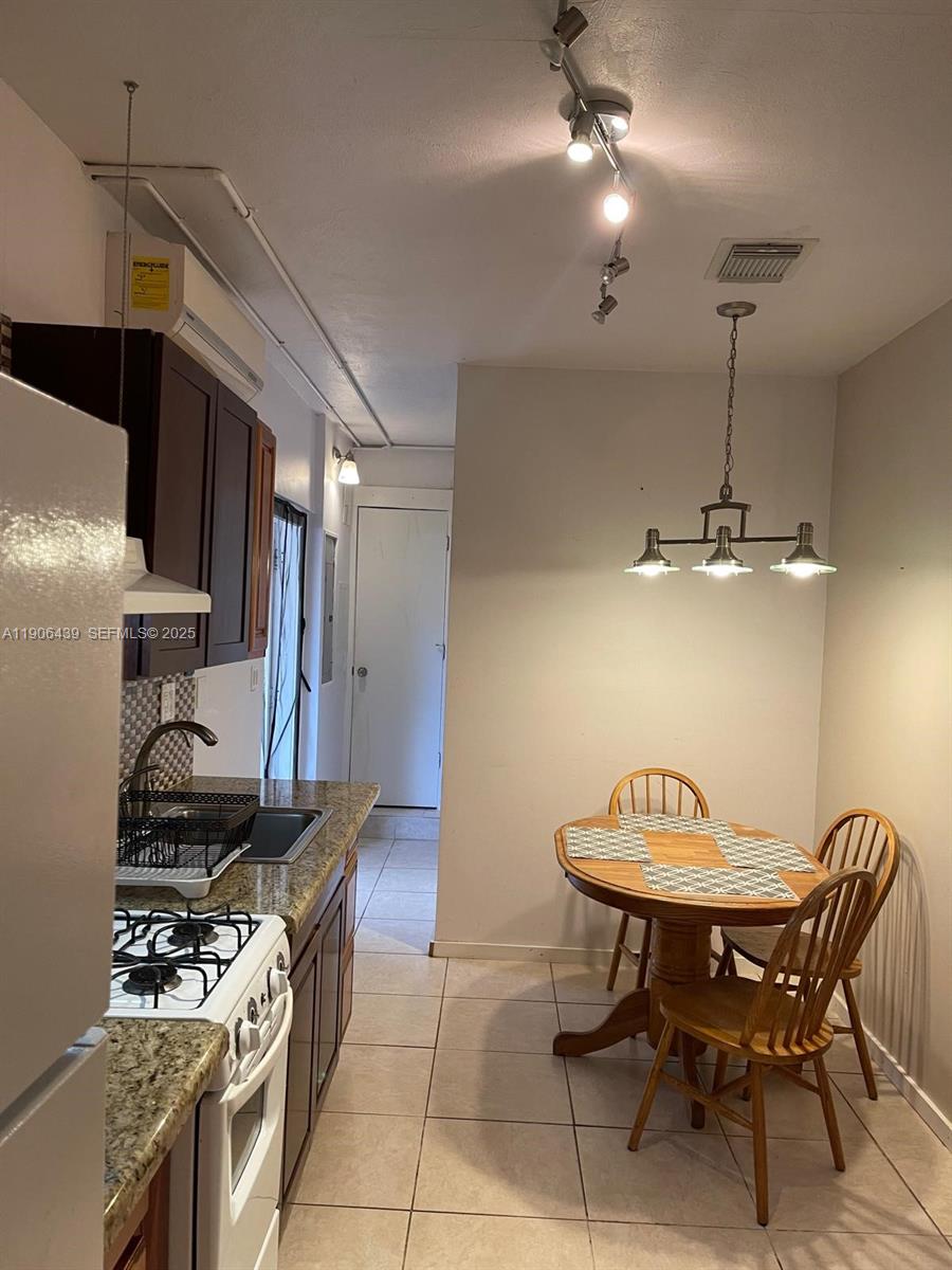 8635 Southwest 102nd Avenue Miami, FL 33173 - Photo 5 of 19 a kitchen with stainless steel appliances granite countertop a stove a chimney a dining table and chairs