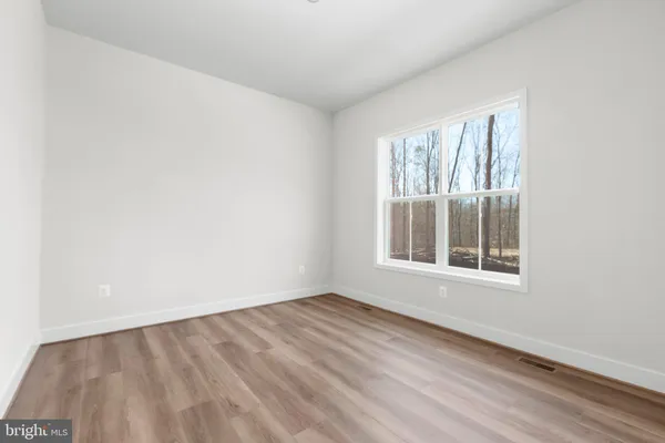 a view of an empty room with wooden floor and closet
